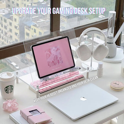 Aesthetic pink and white gaming desk setup with an iPad, laptop, pink keyboard, accessories, and wireless headphones displayed on the Aluminum Gaming Headphone Stand by a large window overlooking city views.