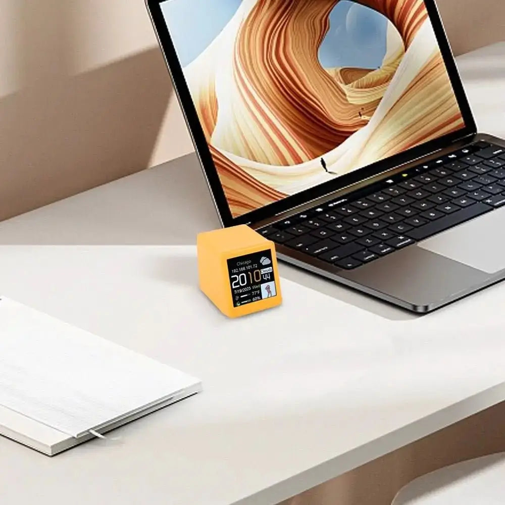 Mini smart weather station in yellow placed on a desk with digital display on