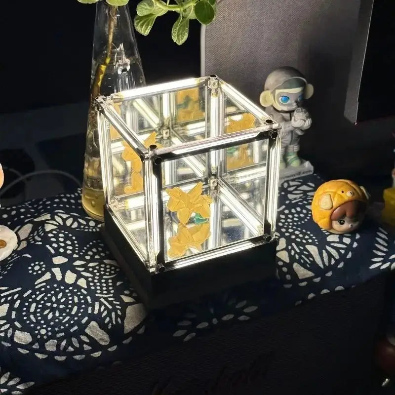 Cube desk lamp with clear mirrored frame and warm golden light inside
