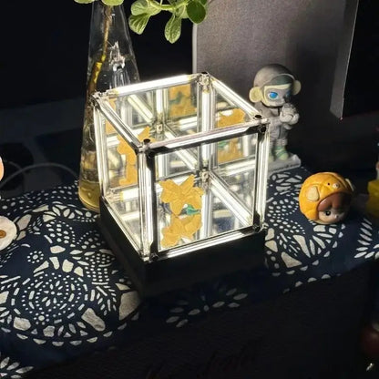 Cube desk lamp with clear mirrored frame and warm golden light inside