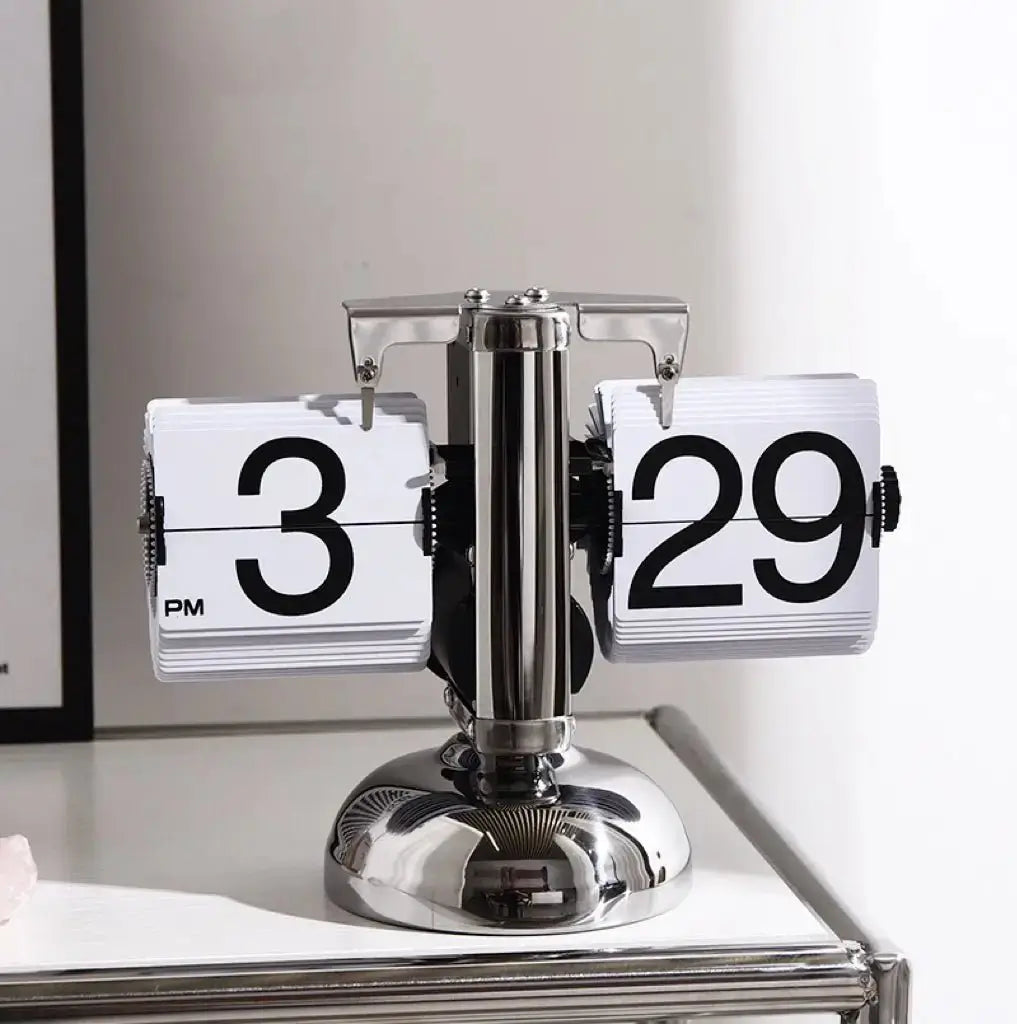 Retro flip clock with white flip pages showing 3 and 29, on chrome pedestal base