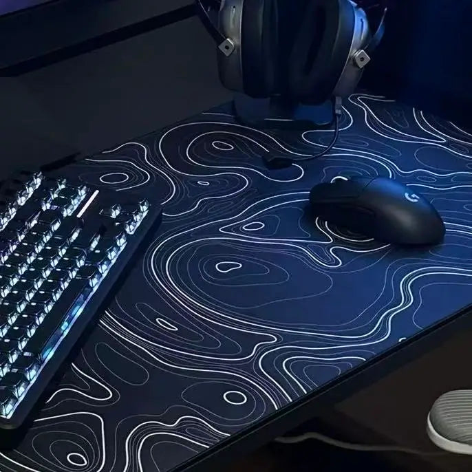 Black desk mat with white contour lines under a computer mouse and keyboard